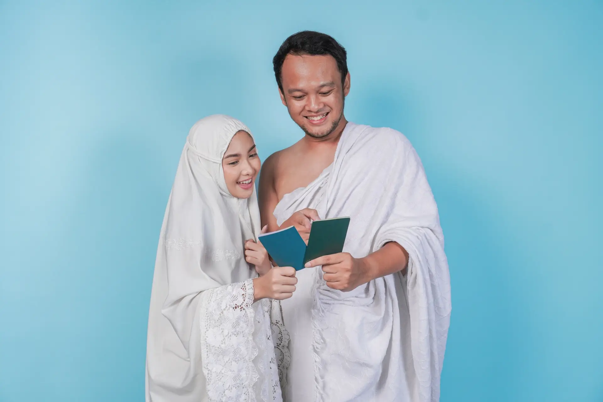 Young Asian Muslim couple in ihram and prayer gown looking at each other passport. Hajj concept.