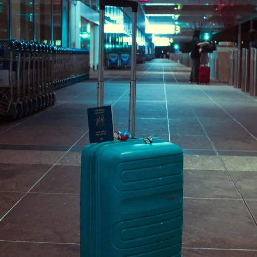 pexels-photo-30782813-30782813 A blue suitcase with a passport in an empty airport terminal at night.